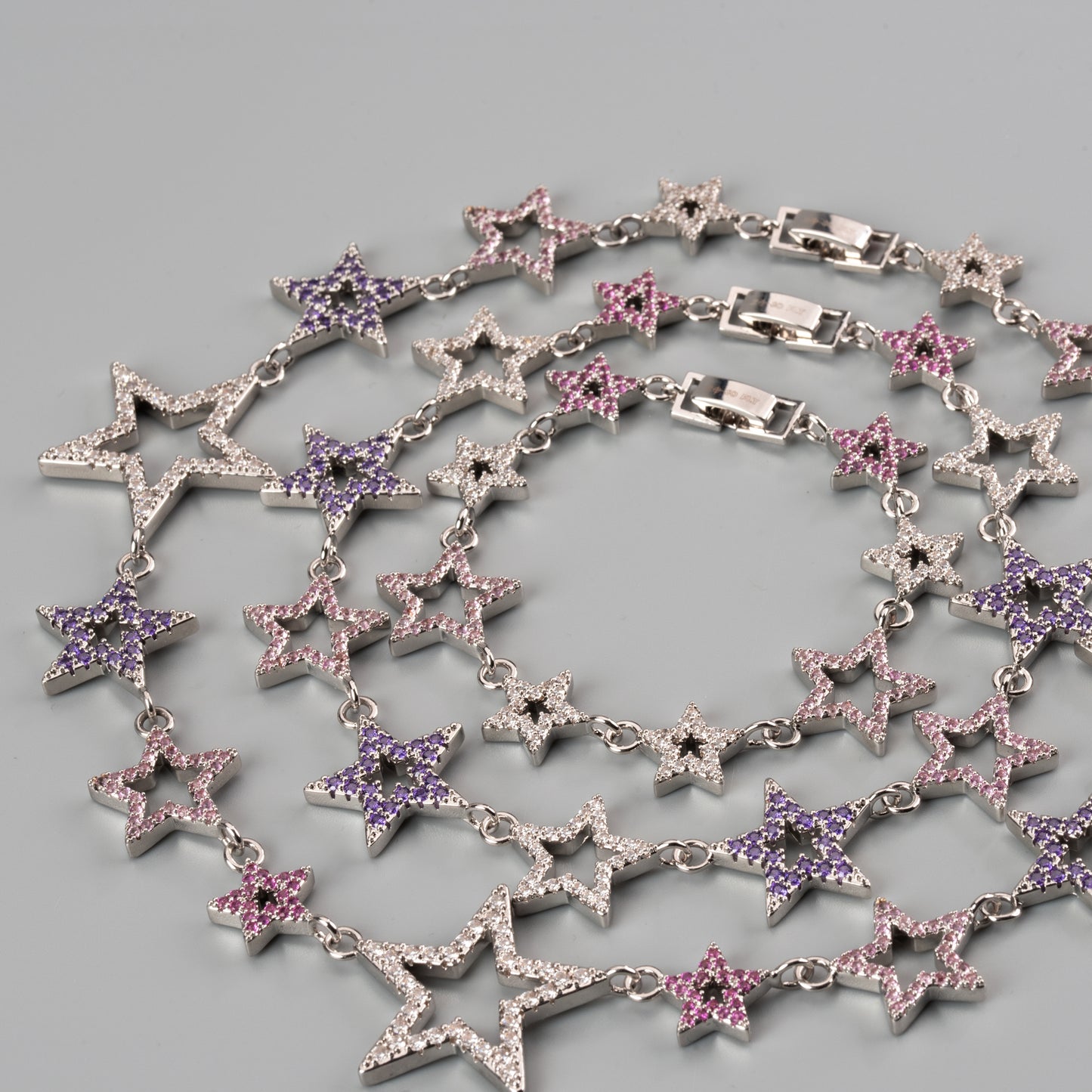 Star-shaped necklace with purple and pink stones on a gray background