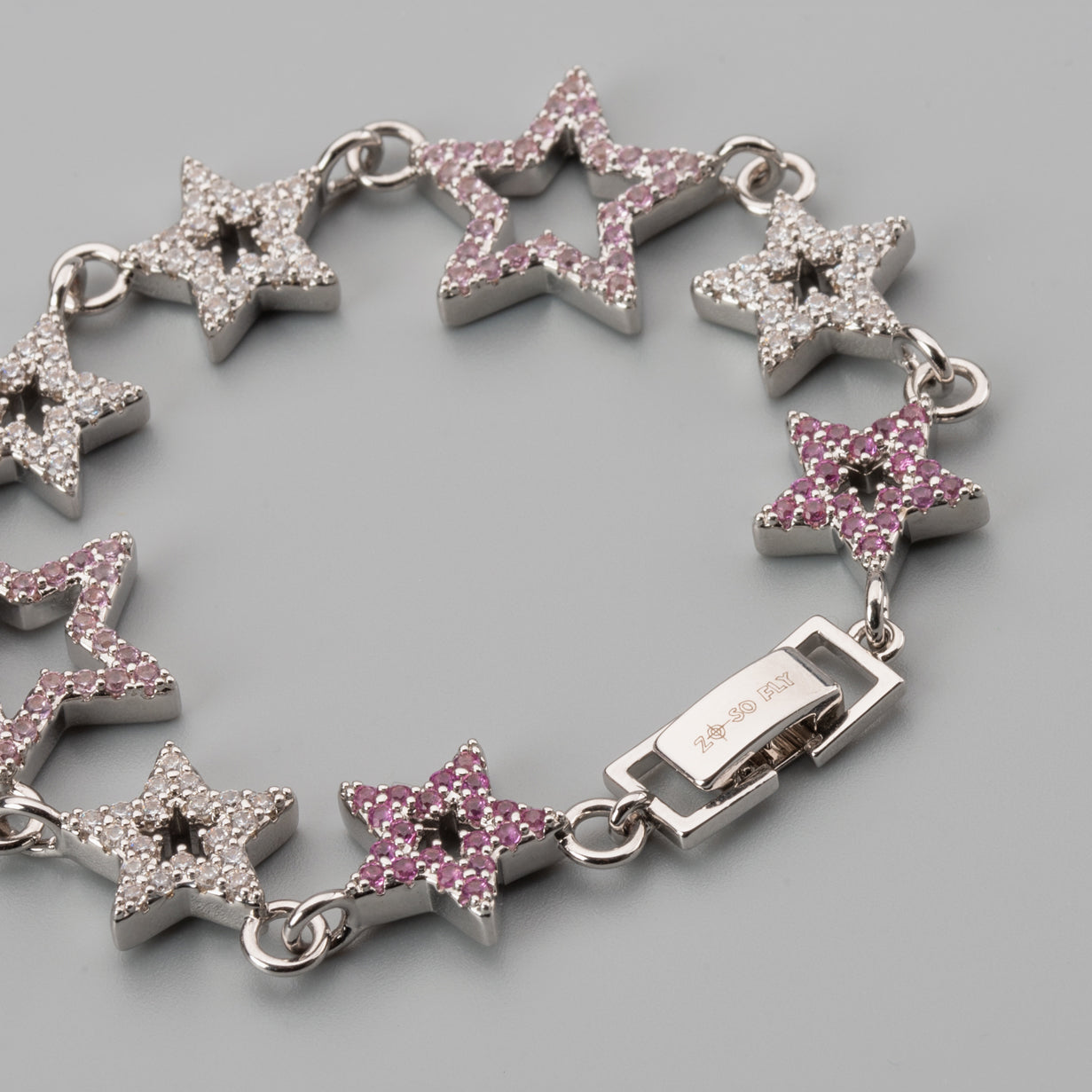 Star-shaped bracelet and luxury collar with pink gemstones on a gray background